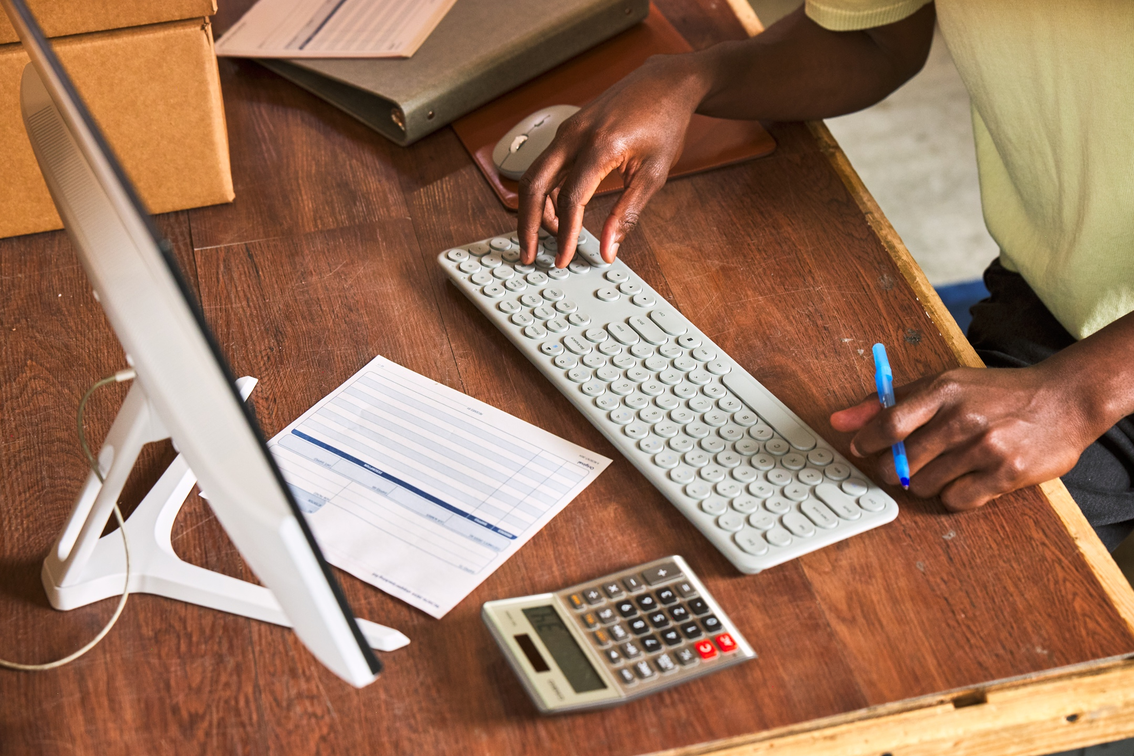 컴퓨터와 계산기를 사용해 아마존 판매 비용을 계산하는 셀러의 모습